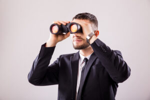 businessman looking through binoculars isolated white wall