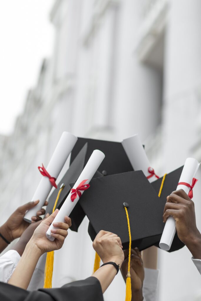 close up hands holding diplomas caps