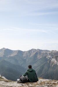 traveler hiking mountains while having his essentials backpack