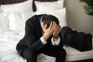 stressed upset businessman sitting bed having headache