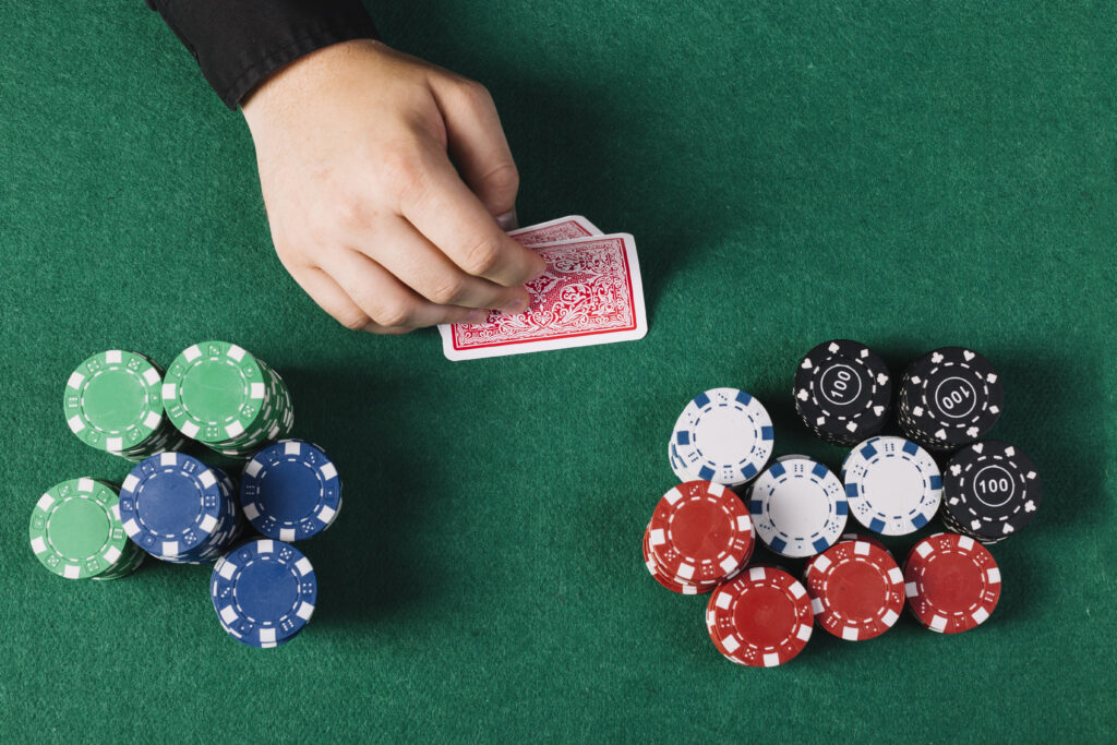 high angle view player s hand with playing cards near poker table